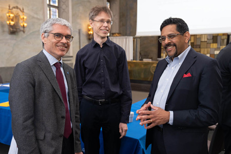 Three men in a lecture hall.