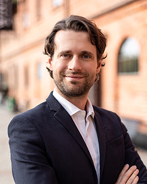 En man står famför en tegelbyggnad