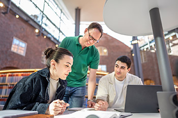 A librarian and two students looking at a computer.