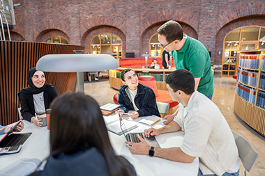 A teacher talks with students around a table. 